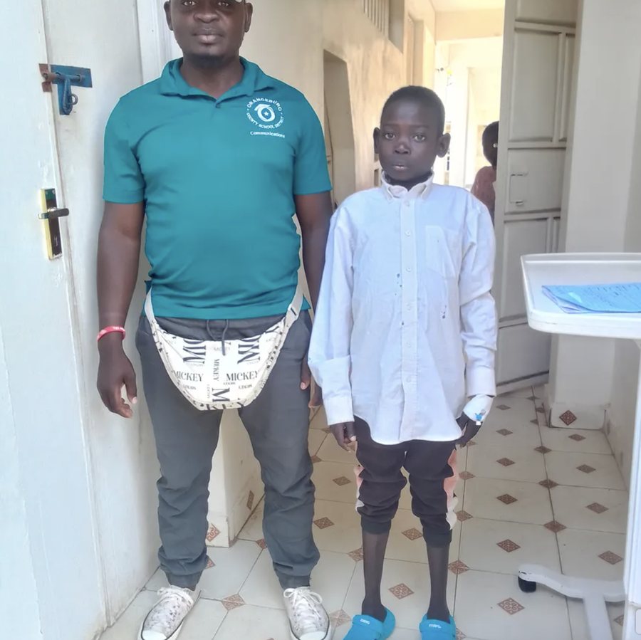 Joseph in a white shirt standing beside a man in the hospital corridor